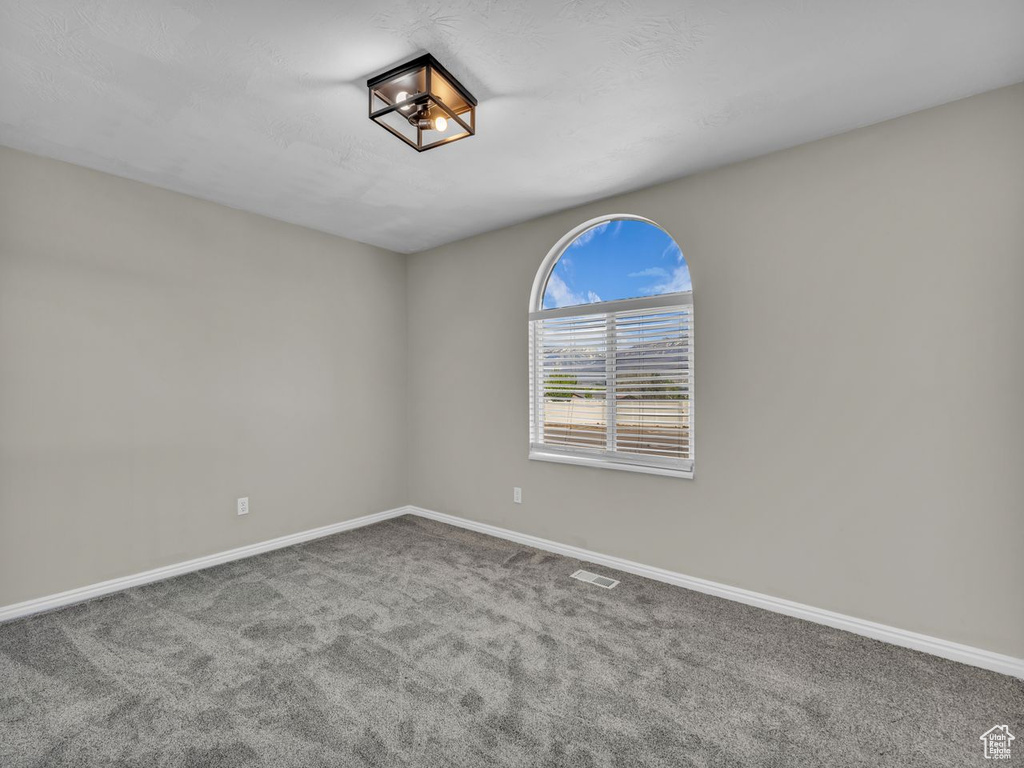 Spare room featuring carpet, visible vents, and baseboards