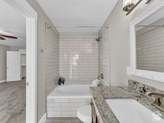 Full bath with a ceiling fan, tiled shower / bath, vanity, and toilet