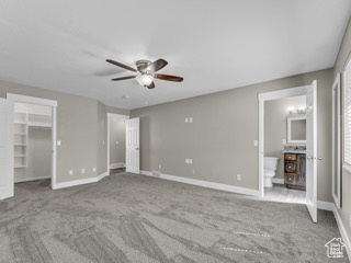 Unfurnished bedroom with baseboards, carpet flooring, ensuite bath, and a spacious closet