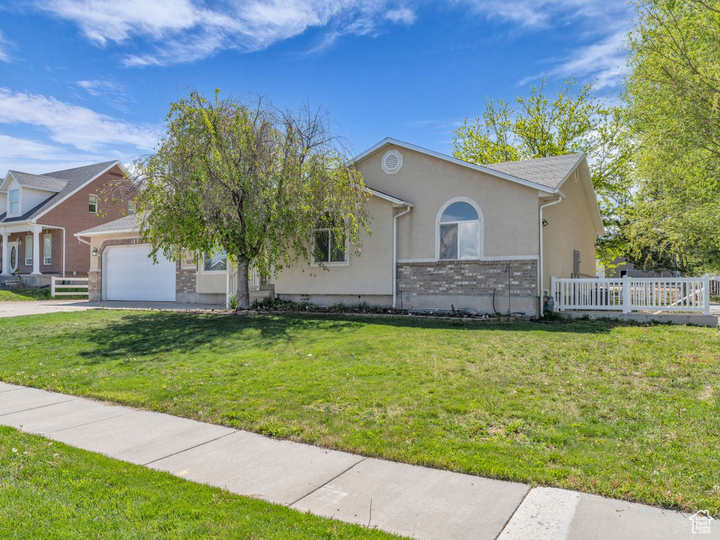Ranch-style house with fence, an attached garage, stucco siding, concrete driveway, and a front yard