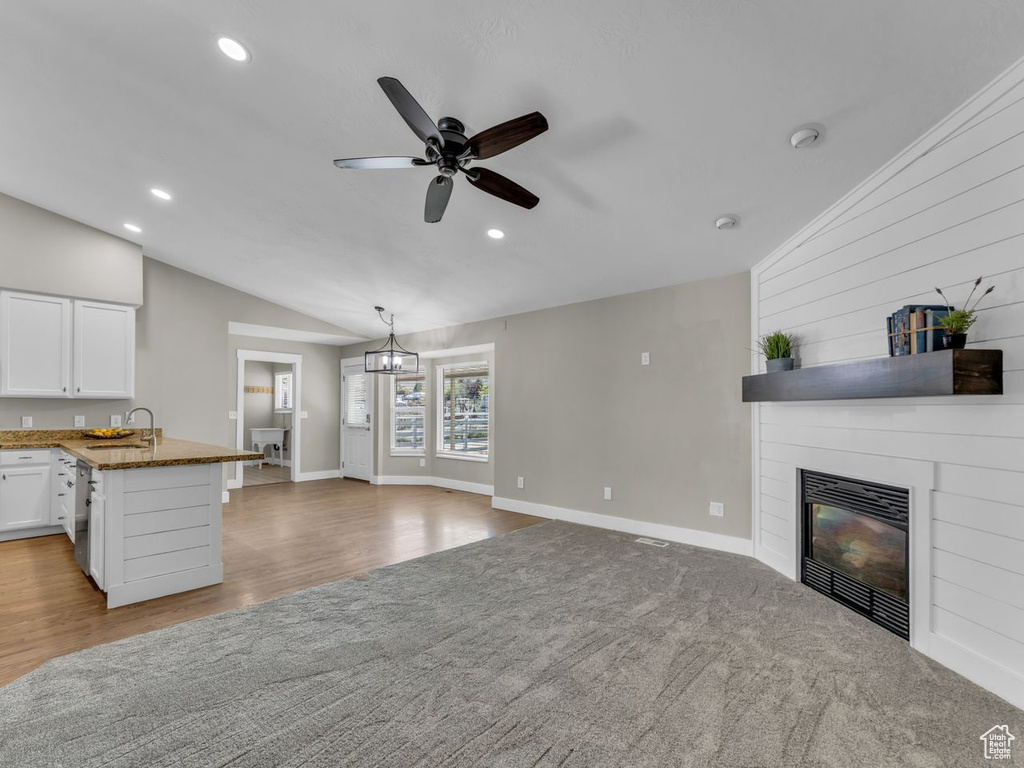 Unfurnished living room featuring lofted ceiling, recessed lighting, a sink, ceiling fan with notable chandelier, and a large fireplace