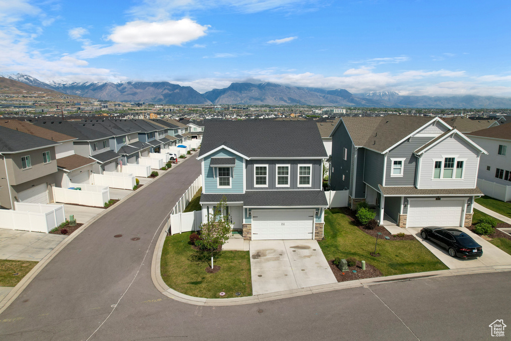 View of front of home with a residential view, an attached garage, concrete driveway, and a mountain view