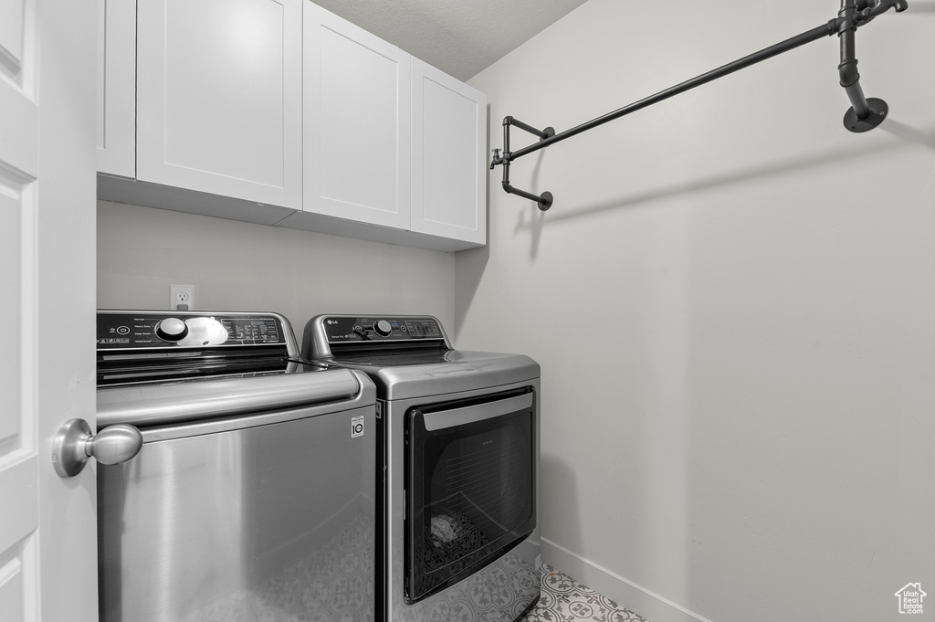 Washroom featuring washing machine and clothes dryer, cabinet space, and baseboards