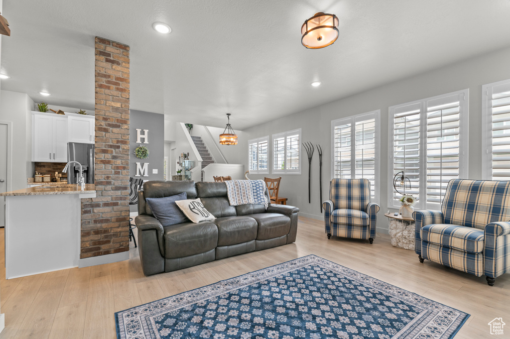 Living area with light wood-style flooring, stairway, recessed lighting, and baseboards
