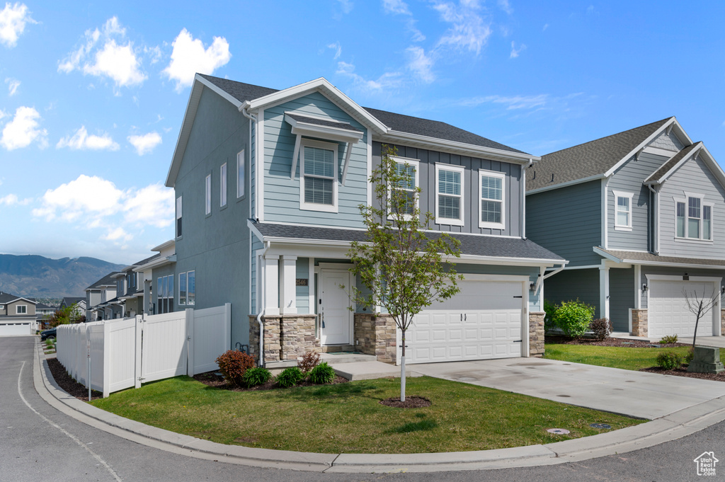 Craftsman house featuring a garage, concrete driveway, a mountain view, stone siding, and board and batten siding
