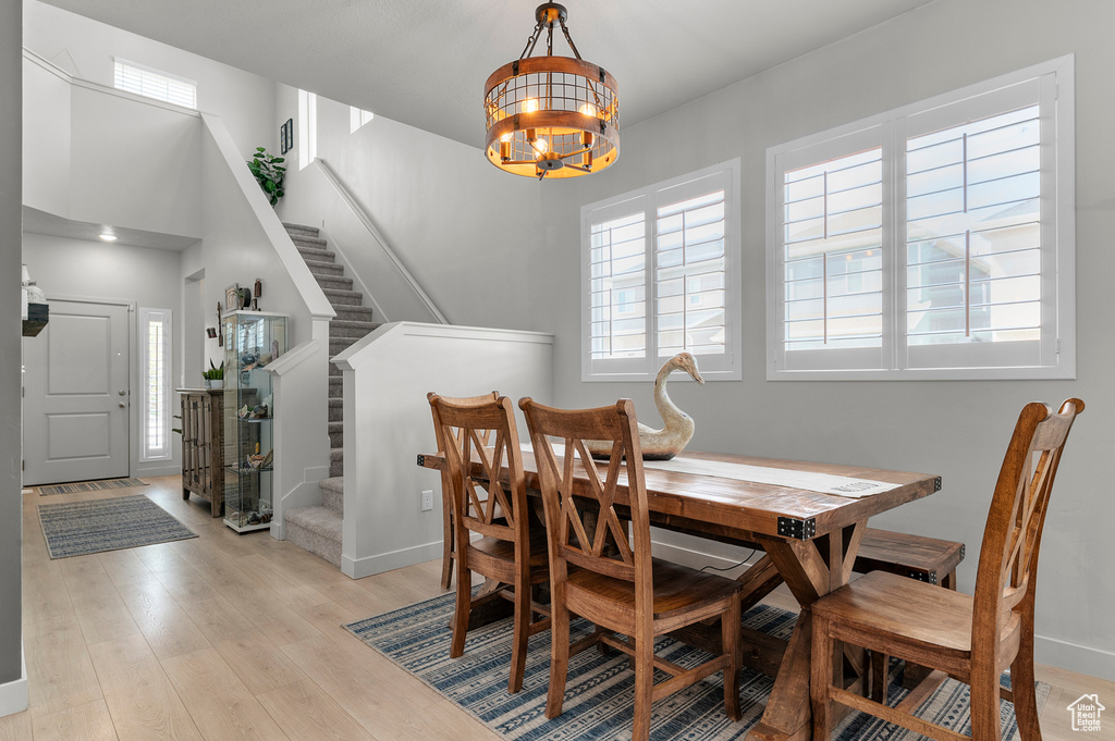 Dining room featuring a chandelier, stairs, light wood-type flooring, and baseboards