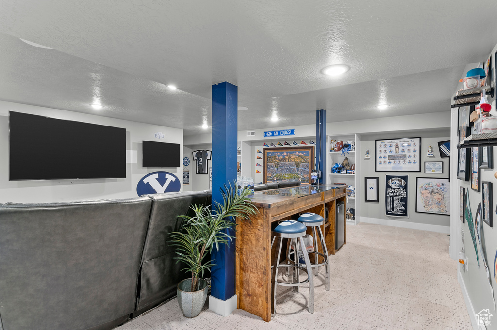 Indoor bar featuring a textured ceiling, recessed lighting, and baseboards