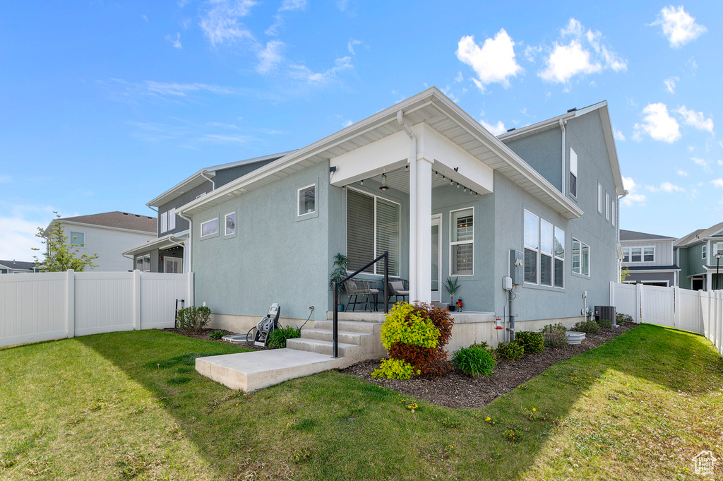Back of property with covered porch, central air condition unit, and stucco siding