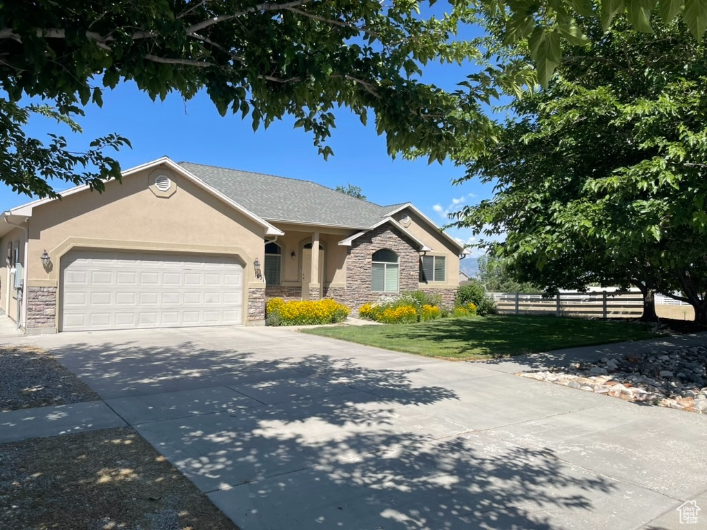 View of front facade with stone siding, stucco siding, an attached garage, and driveway