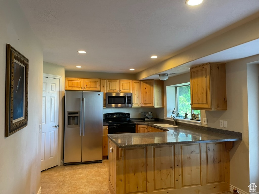 Kitchen featuring stainless steel appliances, a sink, dark stone counters, recessed lighting, and a peninsula