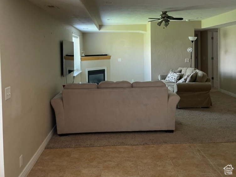 Living area featuring a glass covered fireplace, ceiling fan, and baseboards
