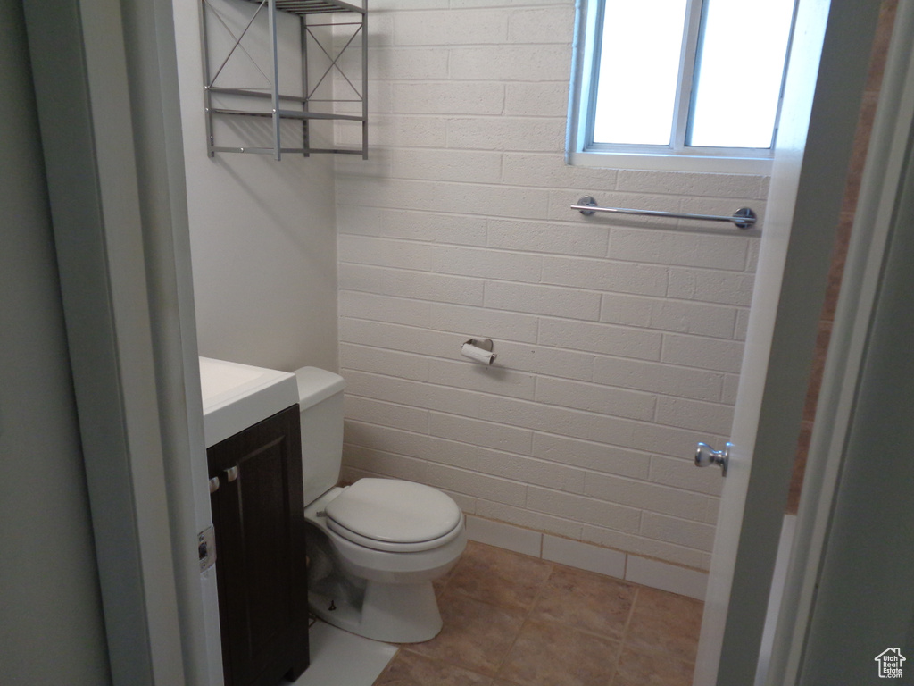 Half bathroom with toilet, vanity, and tile patterned floors
