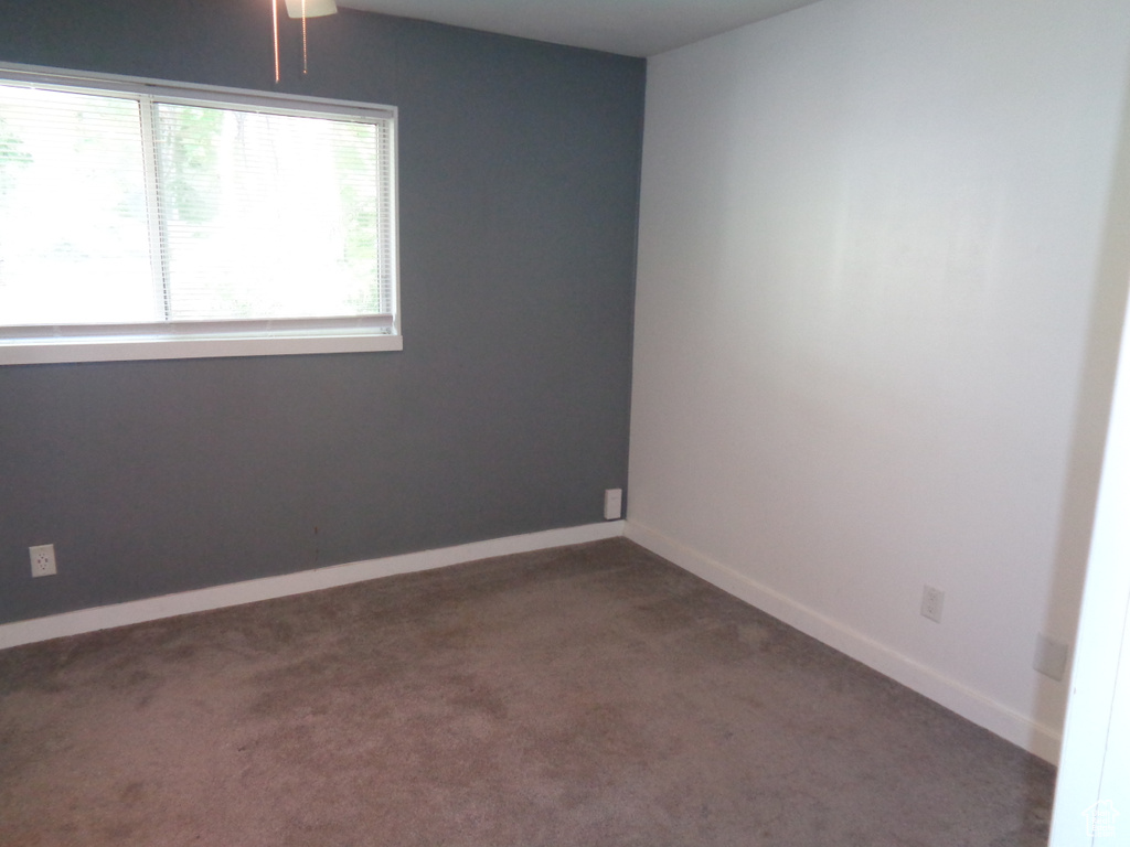 Empty room featuring dark colored carpet and baseboards