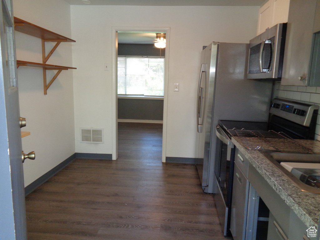 Kitchen with stainless steel appliances, backsplash, dark wood-style flooring, and baseboards