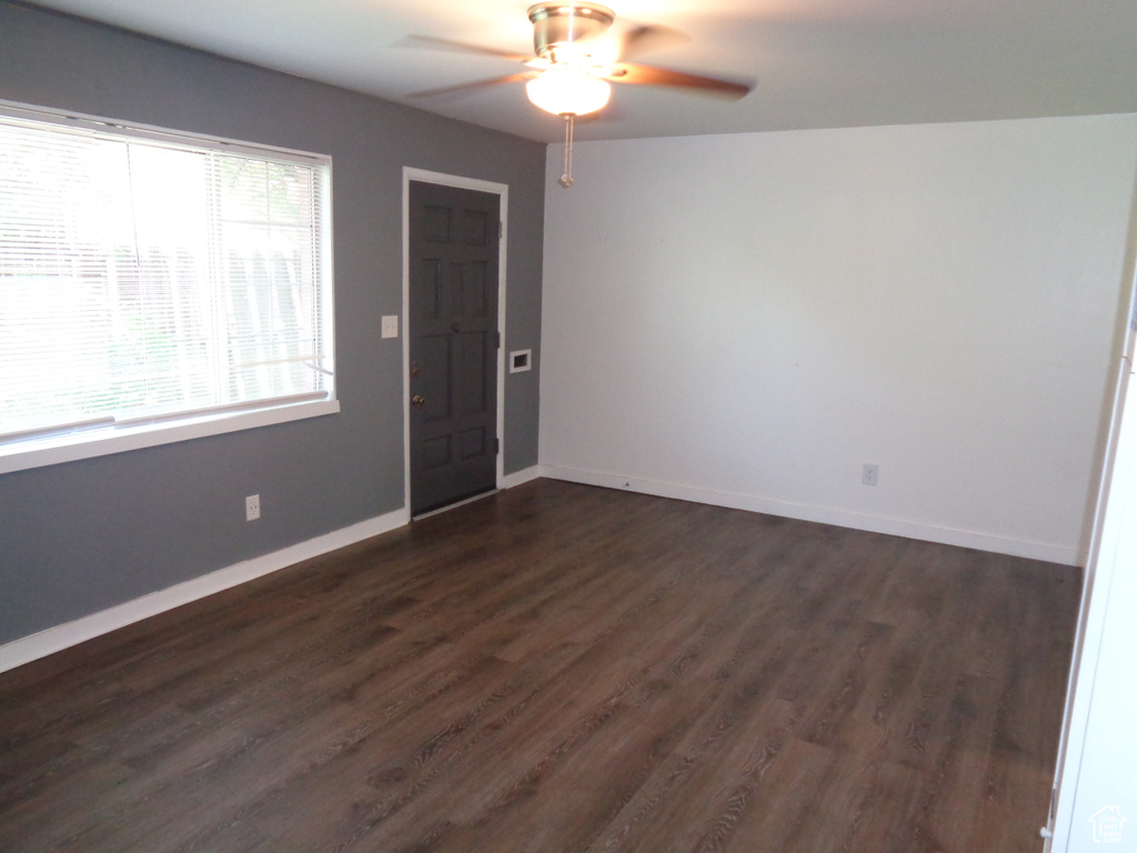 Unfurnished room featuring a ceiling fan, dark wood-style flooring, and baseboards