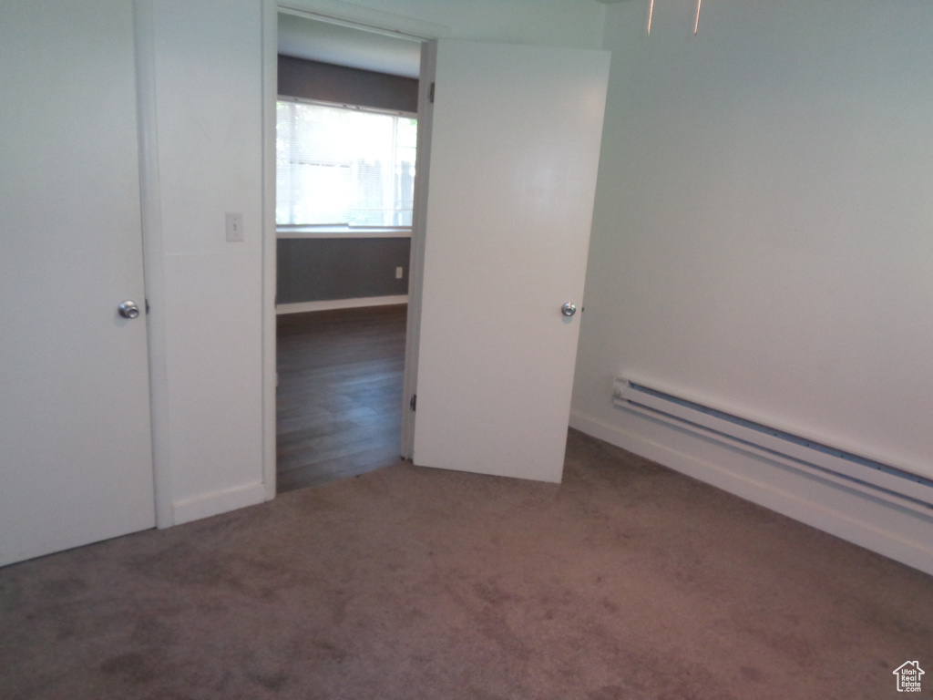Unfurnished bedroom featuring carpet and baseboard heating