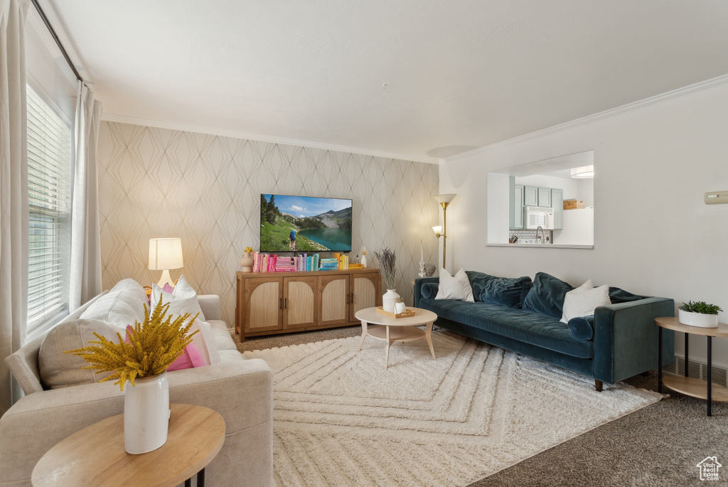 Living area featuring carpet floors, crown molding, and an accent wall