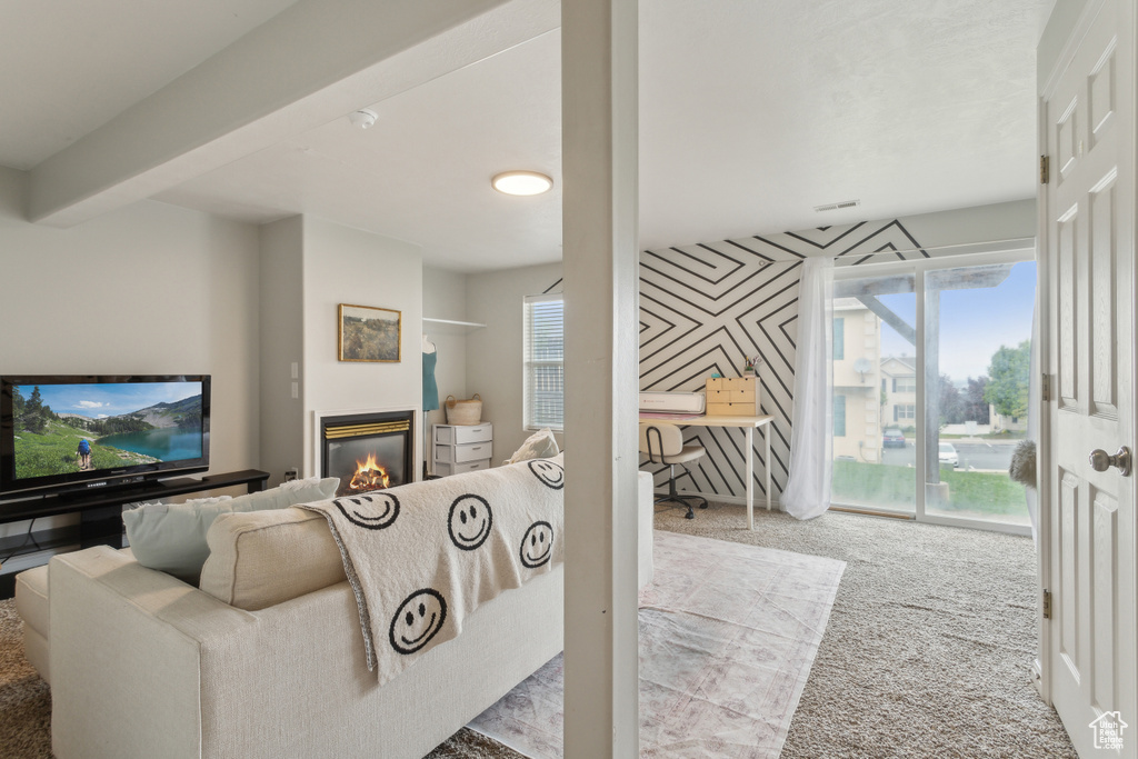 Living room with carpet, a glass covered fireplace, an office area, and plenty of natural light