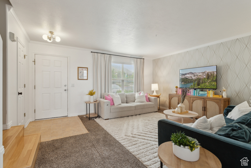Carpeted living room with ornamental molding, baseboards, and wallpapered walls