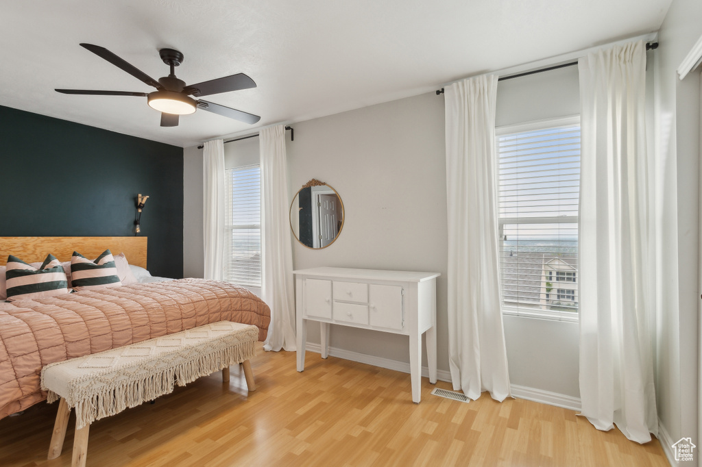 Bedroom with baseboards, a ceiling fan, multiple windows, and wood finished floors