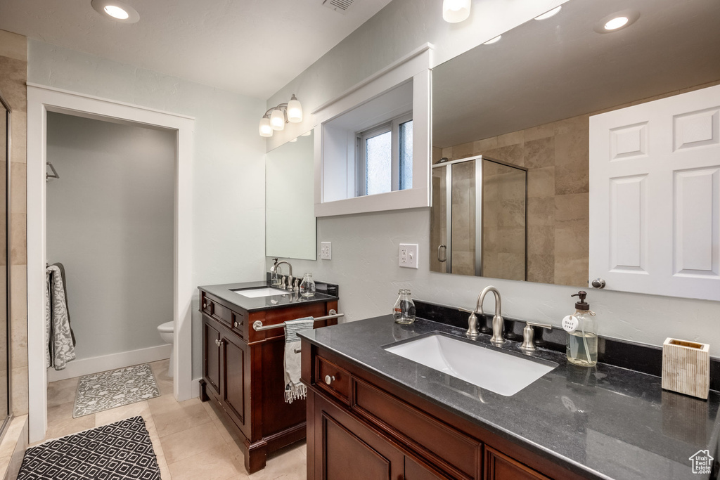 Bathroom with a shower stall, recessed lighting, two vanities, tile patterned flooring, and toilet
