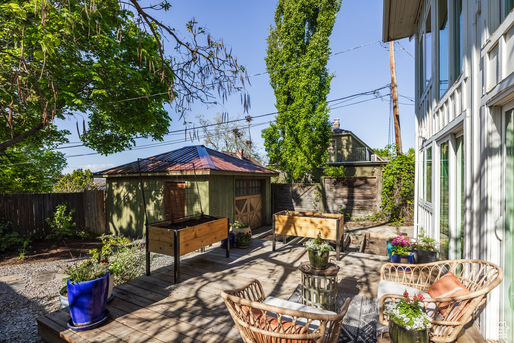 View of patio / terrace with a fenced backyard, a wooden deck, and an outbuilding