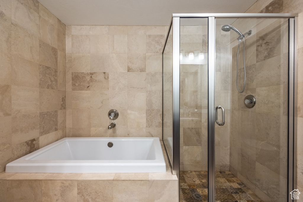 Full bath with a shower stall and tiled bath