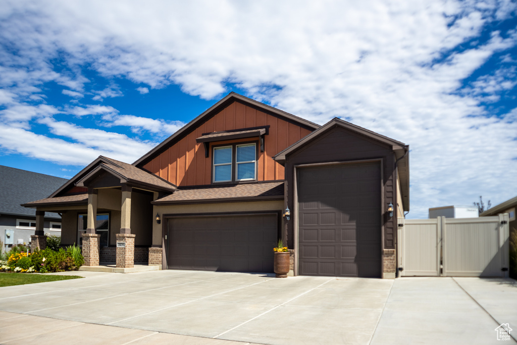 Craftsman-style house featuring driveway, a gate, board and batten siding, an attached garage, and fence