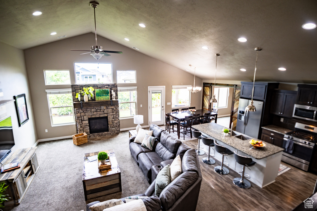 Carpeted living room featuring recessed lighting, a stone fireplace, a ceiling fan, baseboards, and high vaulted ceiling