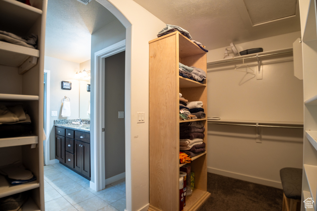 Spacious closet featuring arched walkways and light tile patterned flooring