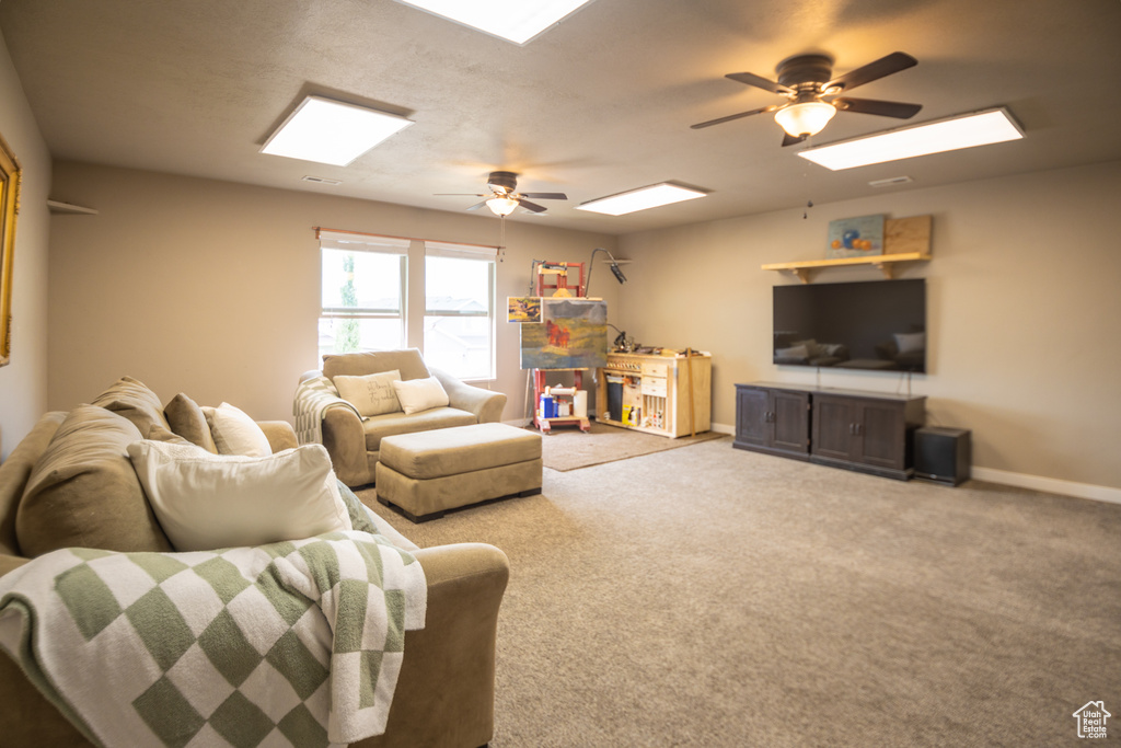 Living room with a ceiling fan, baseboards, and carpet floors