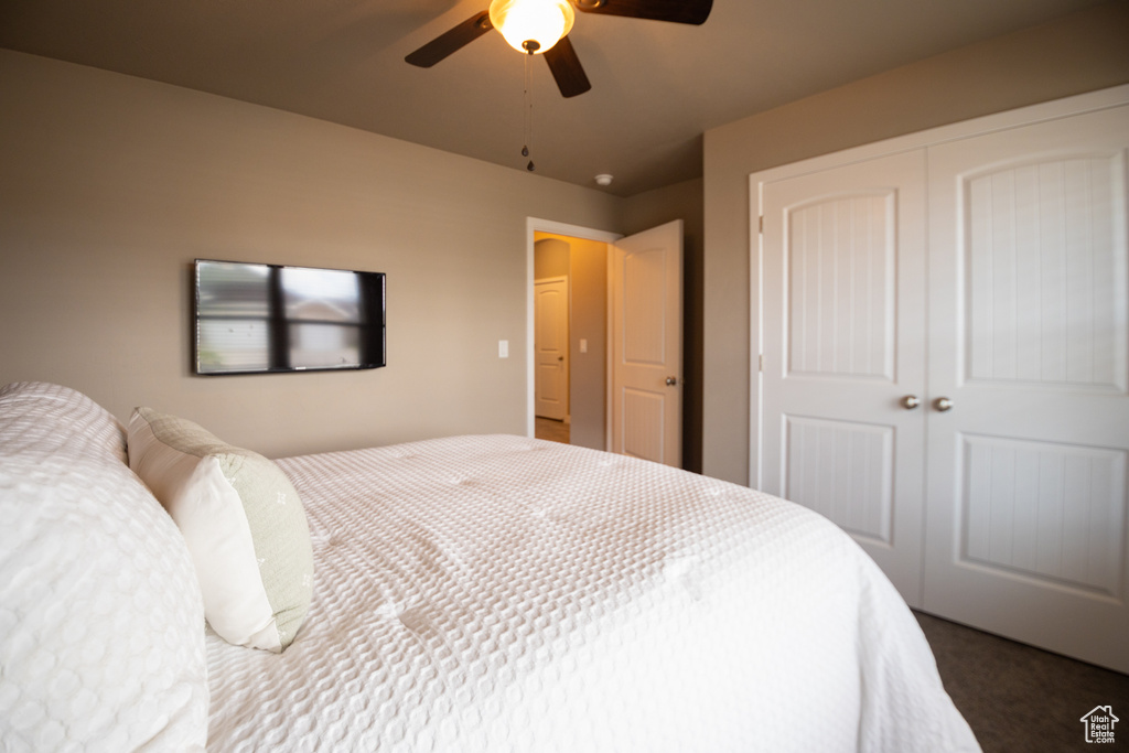 Bedroom featuring a closet, dark carpet, and ceiling fan