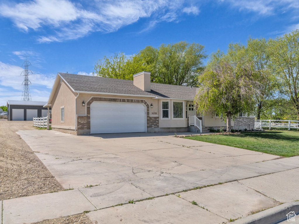 Ranch-style house with a chimney, fence, an attached garage, concrete driveway, and a front yard
