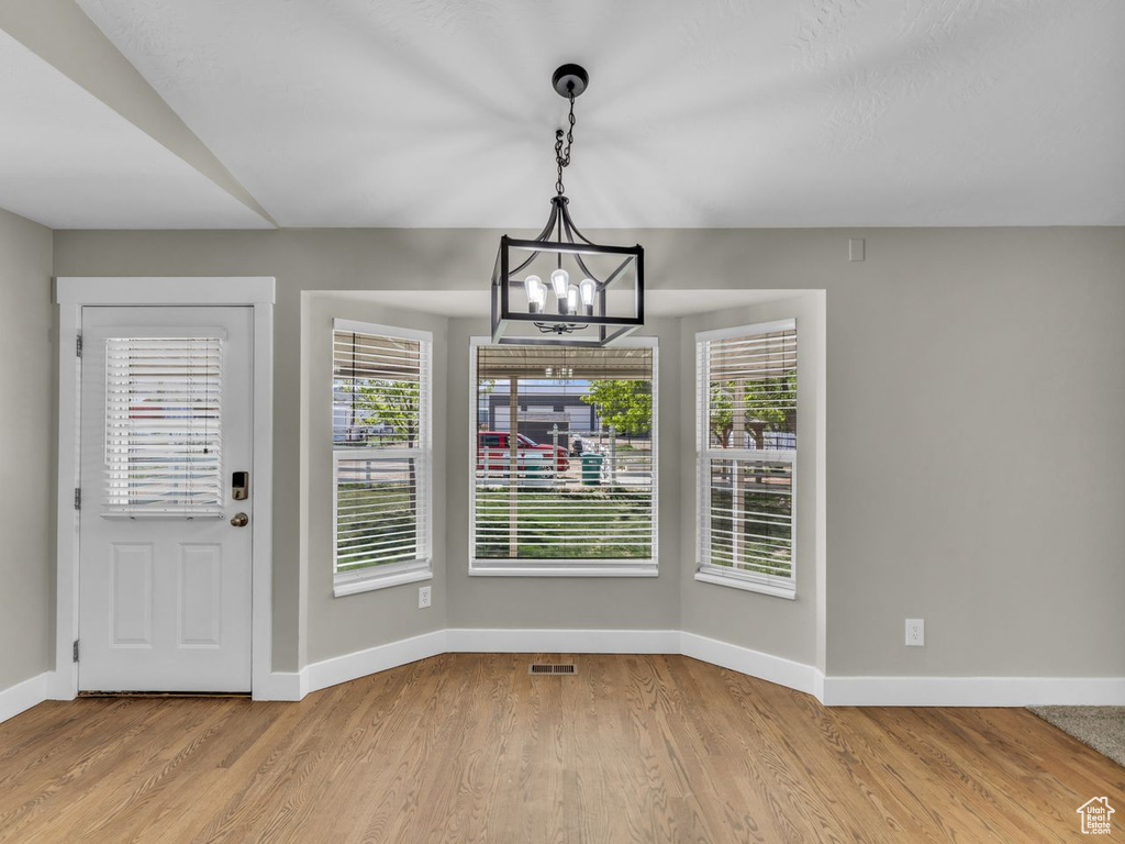 Interior space featuring baseboards, an inviting chandelier, and wood finished floors