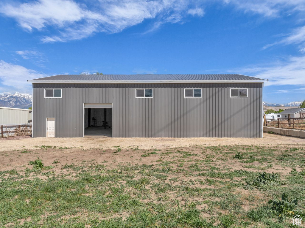 Back of property with a pole building, fence, metal roof, and an outdoor structure