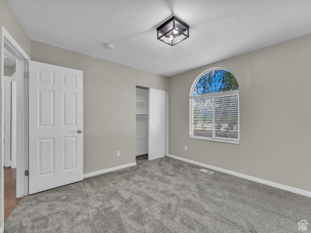 Unfurnished bedroom featuring baseboards, a closet, visible vents, and carpet