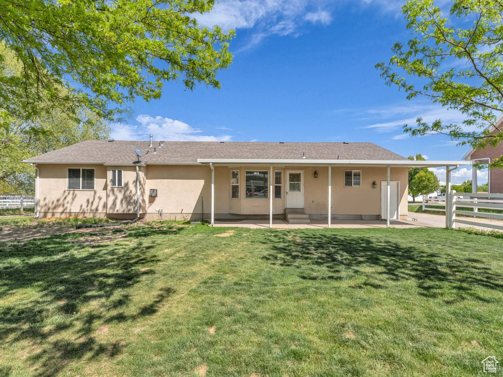 Rear view of property featuring a patio, stucco siding, fence, a lawn, and entry steps