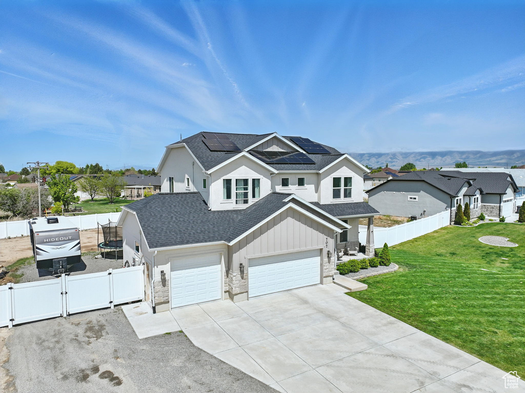 View of front of house with a gate, roof with shingles, solar panels, driveway, and an attached garage