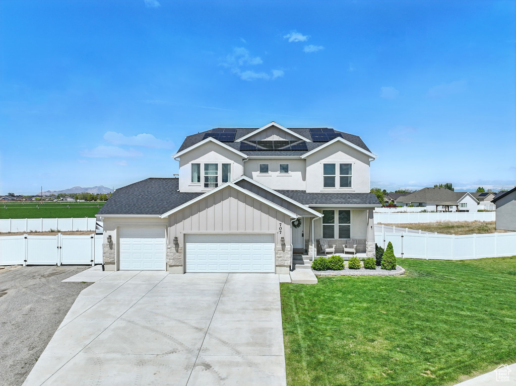Craftsman-style home with stone siding, solar panels, concrete driveway, a shingled roof, and a gate
