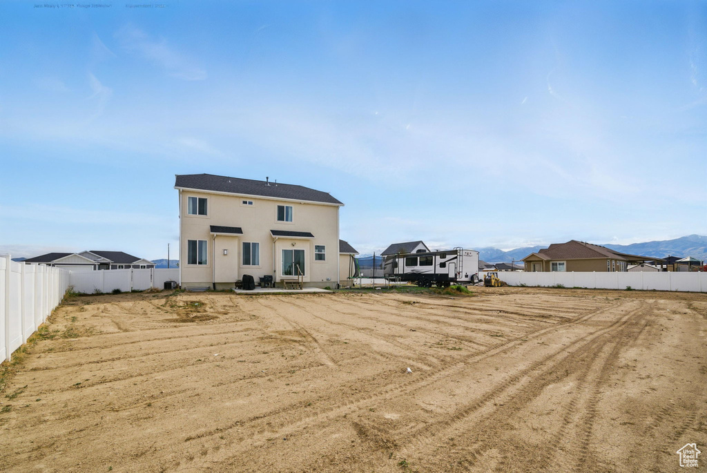 Back of house with a fenced backyard, a mountain view, and stucco siding