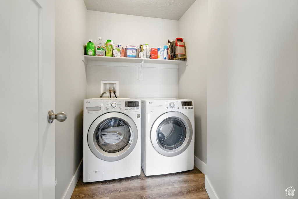 Laundry area featuring washer and dryer, wood finished floors, and baseboards