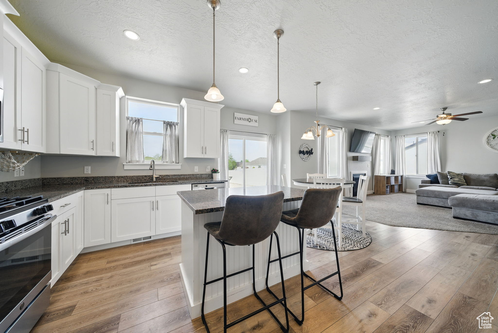 Kitchen with gas range, a sink, a textured ceiling, a kitchen breakfast bar, and open floor plan