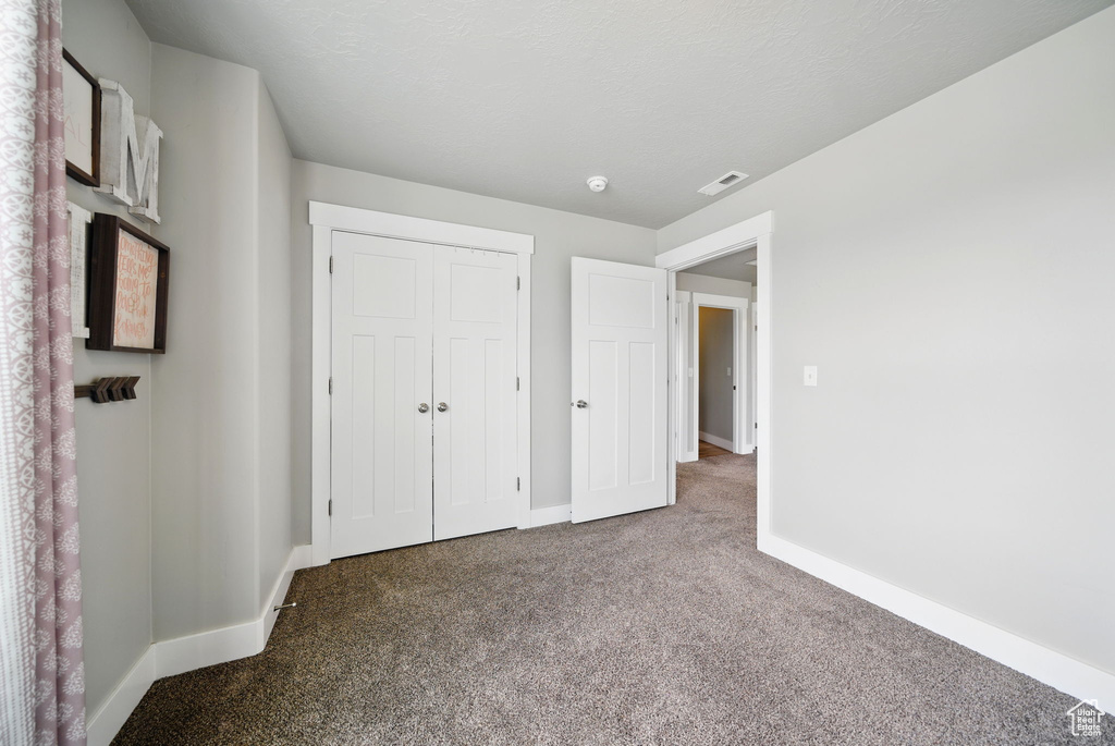 Unfurnished bedroom with carpet flooring, baseboards, and a closet