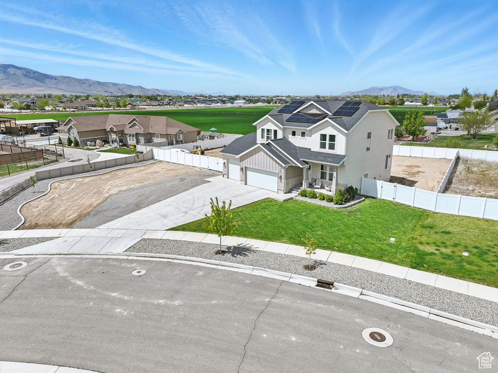 View of front of property featuring roof mounted solar panels, board and batten siding, a residential view, a mountain view, and concrete driveway