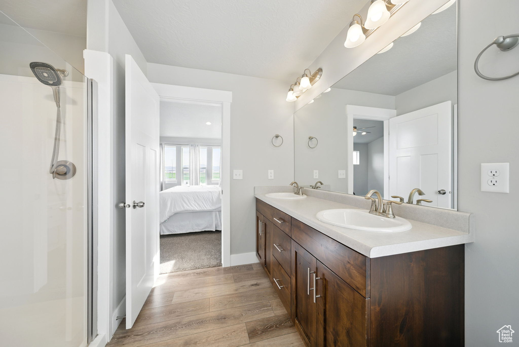 Full bathroom featuring wood finished floors, an enclosed shower, and a ceiling fan