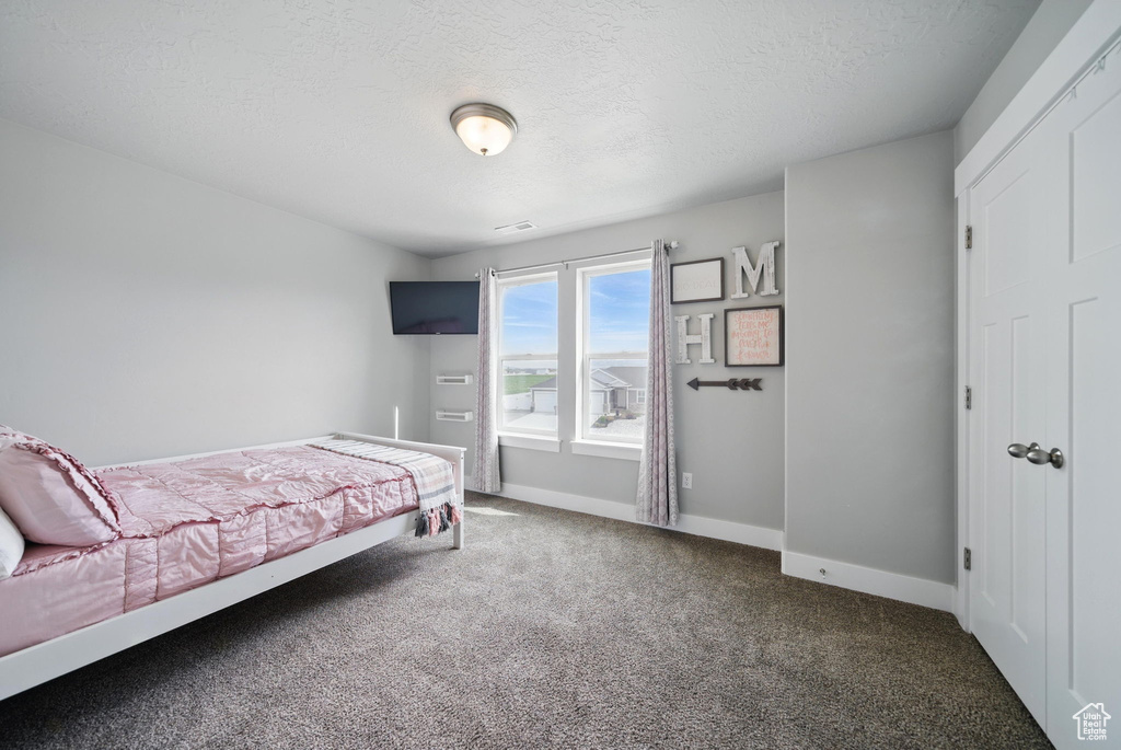 Carpeted bedroom featuring a textured ceiling and baseboards