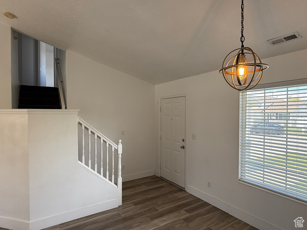 Entrance foyer featuring stairway, dark wood finished floors, baseboards, and a chandelier