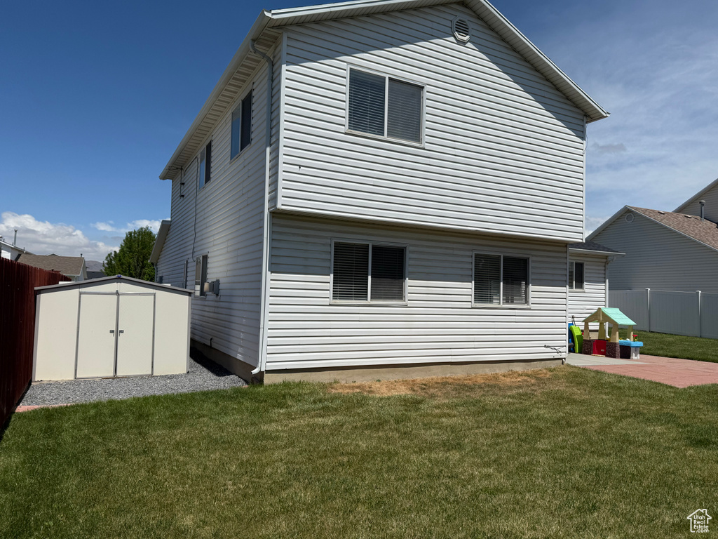 Back of property with a storage shed, a patio area, and an outbuilding