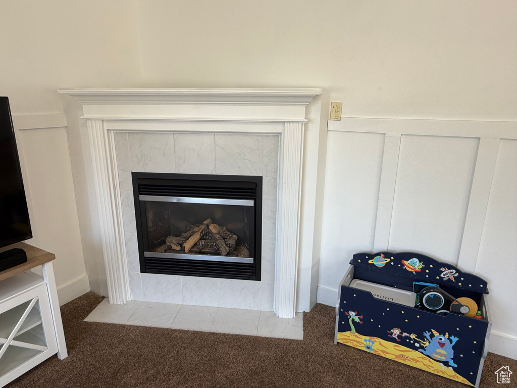 Detailed view of carpet floors, a tile fireplace, and a decorative wall