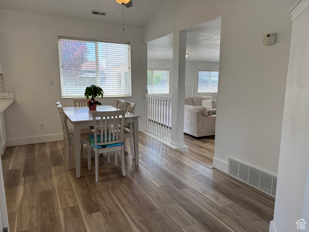 Dining space with wood finished floors, lofted ceiling, and baseboards